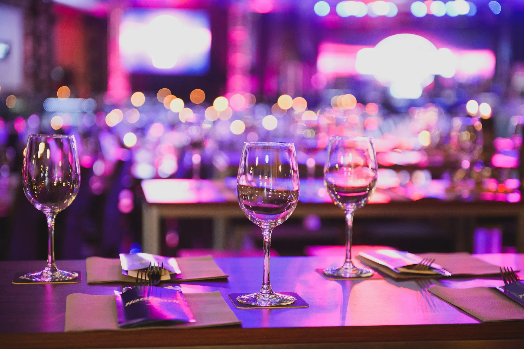 Copas sobre una mesa con luces de fiesta moradas y rosas de fondo