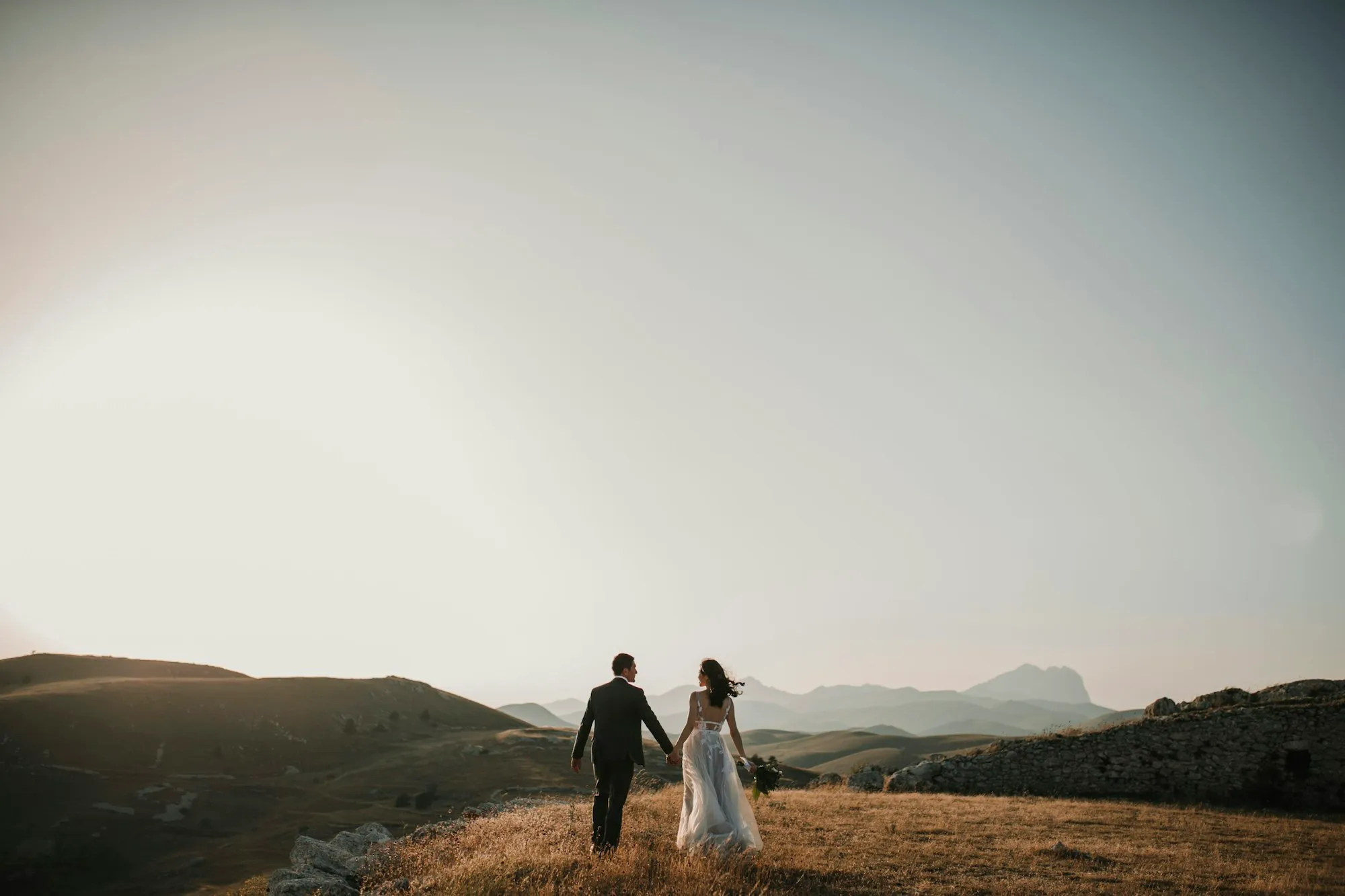 Pareja caminando de la mano por un campo abierto al atardecer